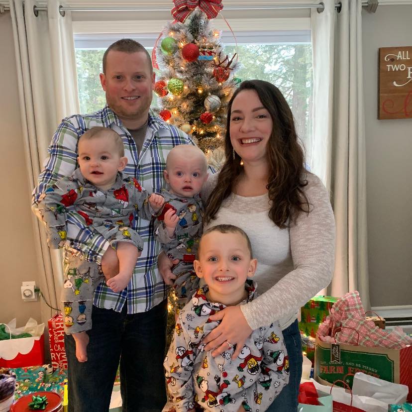 family with twins and a young son in front of a christmas tree