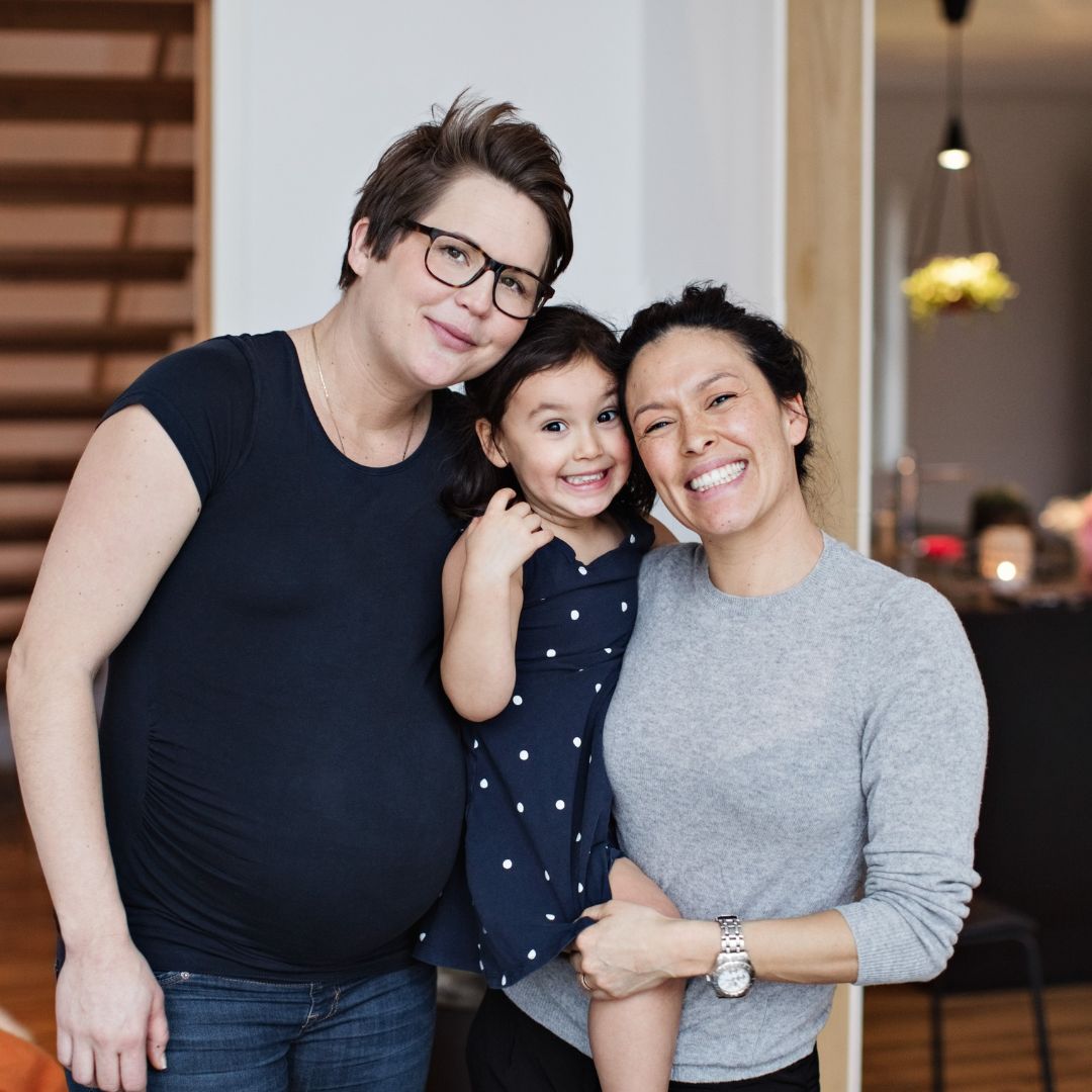 two moms hugging their toddler