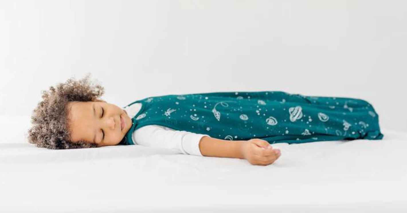tall toddler sleeping on his back in a woolino sleep sack